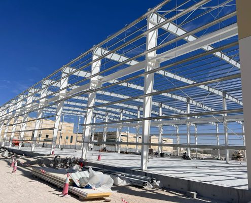 White intumescent-coated steel structural frame under a blue sky at a construction site