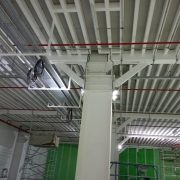Warehouse ceiling with steel beams coated in fire protection paint and exposed cabling