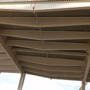 Upward view of steel roof deck and purlins coated with intumescent fireproofing under a canopy
