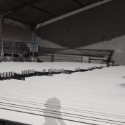 Rows of steel roof purlins coated with white solvent-based intumescent paint at dusk