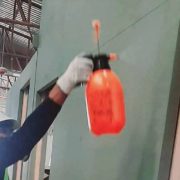Worker using a hand-pump sprayer to apply fire retardant coating to a panel