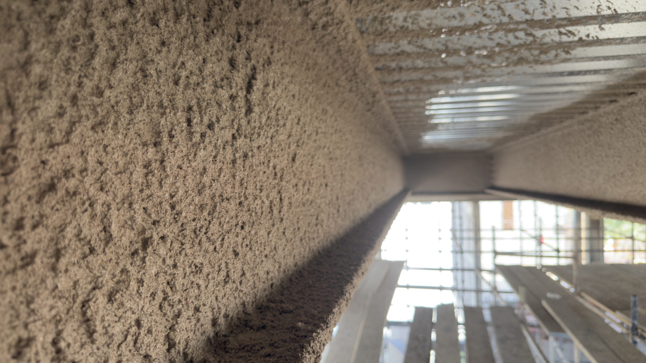 Sprayed cementitious fireproofing on structural steel roof beams inside a building under construction